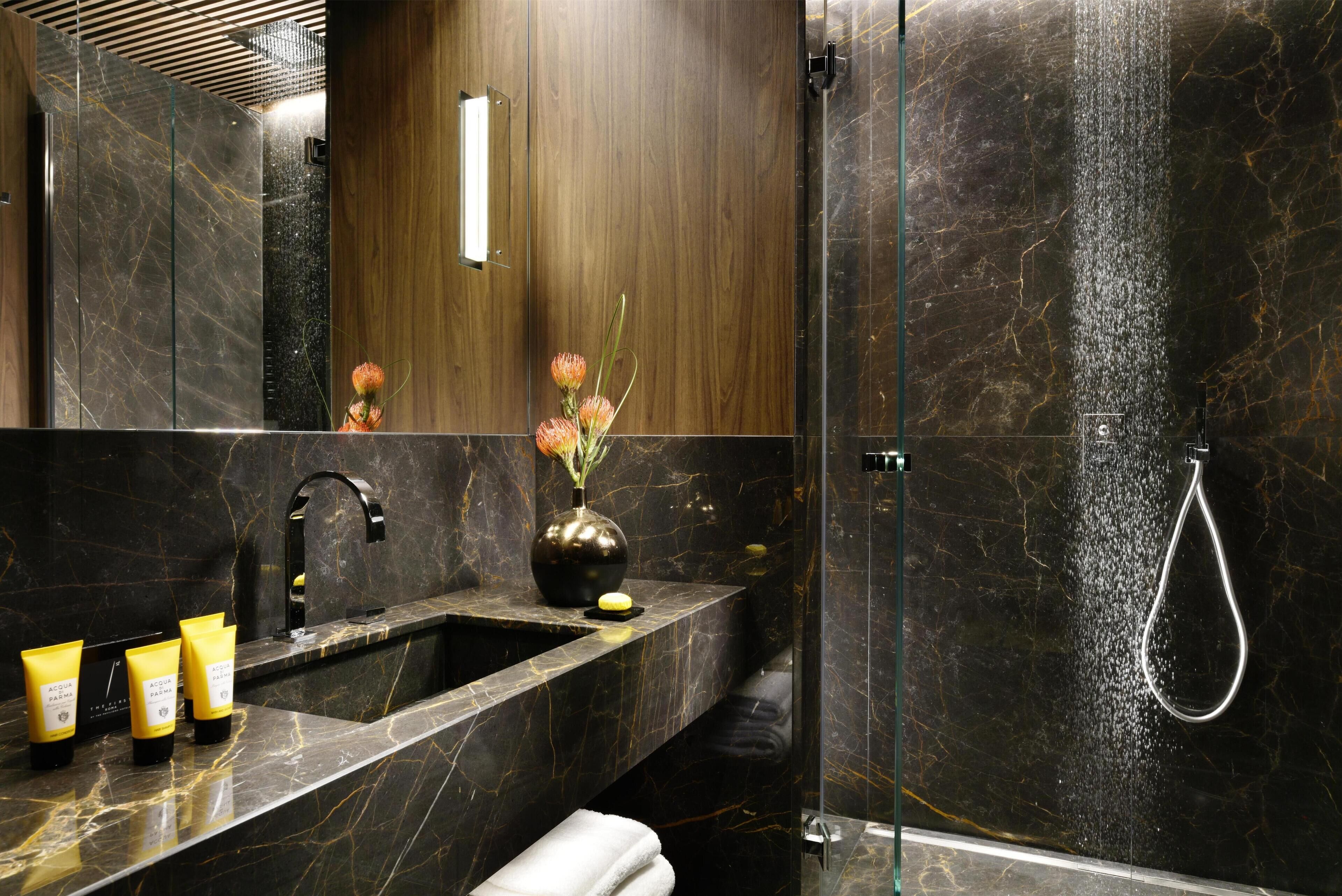 Ein modernes Badezimmer mit Marmorwaschbecken, einem Spiegel, einer Vase mit Blumen und einer Duschkabine.