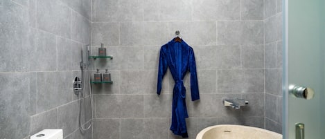 A modern bathroom with a walk-in shower, a bathtub, and a robe hanging on the wall.