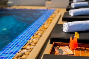A poolside area with lounge chairs, towels, and a tray with a drink and magazine. - Blanc Smith Residence (Siem Reap)
