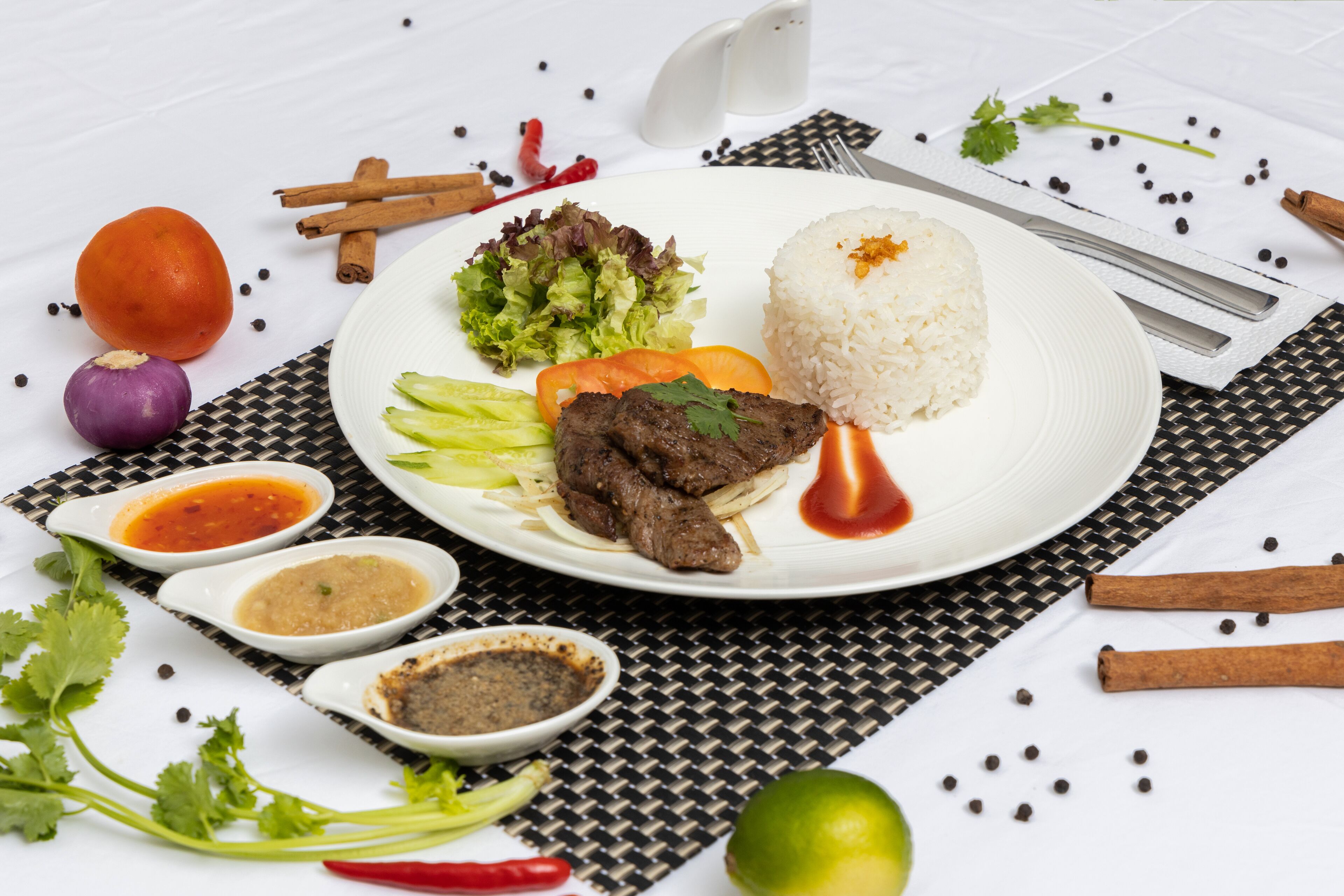 A plate with rice, meat, vegetables, and sauces.