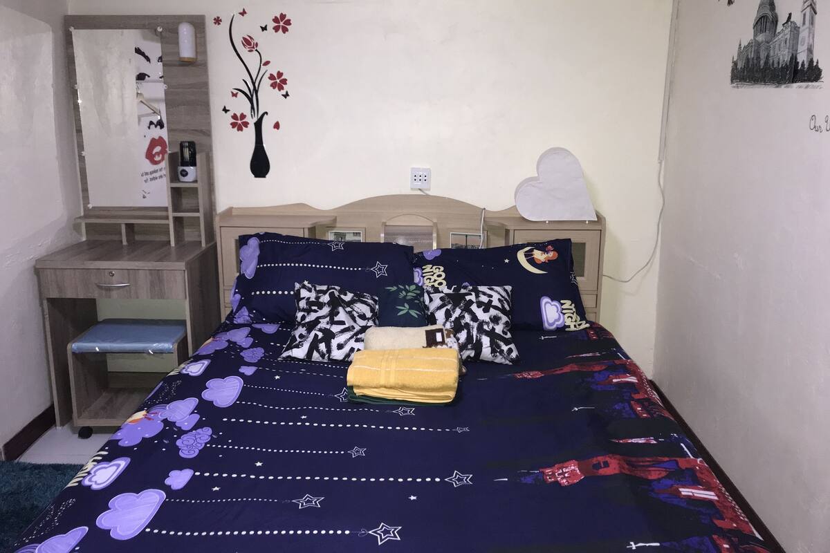 A bedroom with a bed, a desk, and a chair.