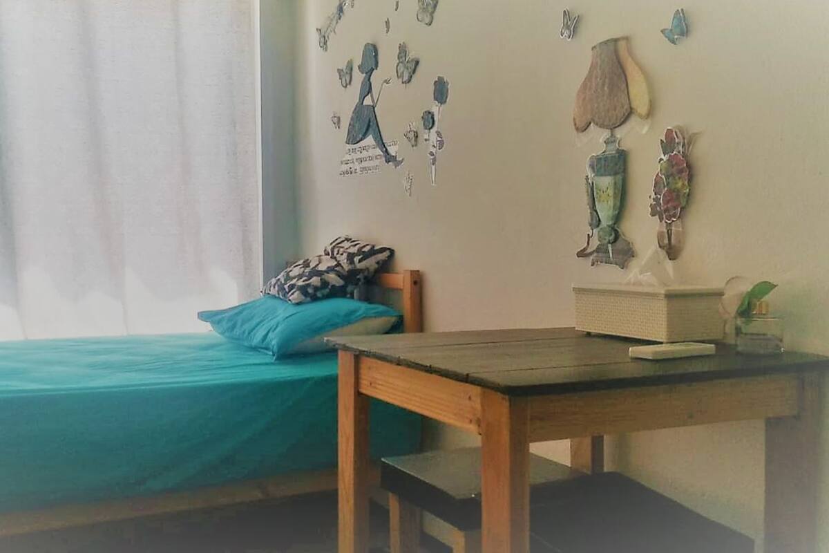 A room with a bed, a wooden table, and a wall decorated with butterfly stickers.