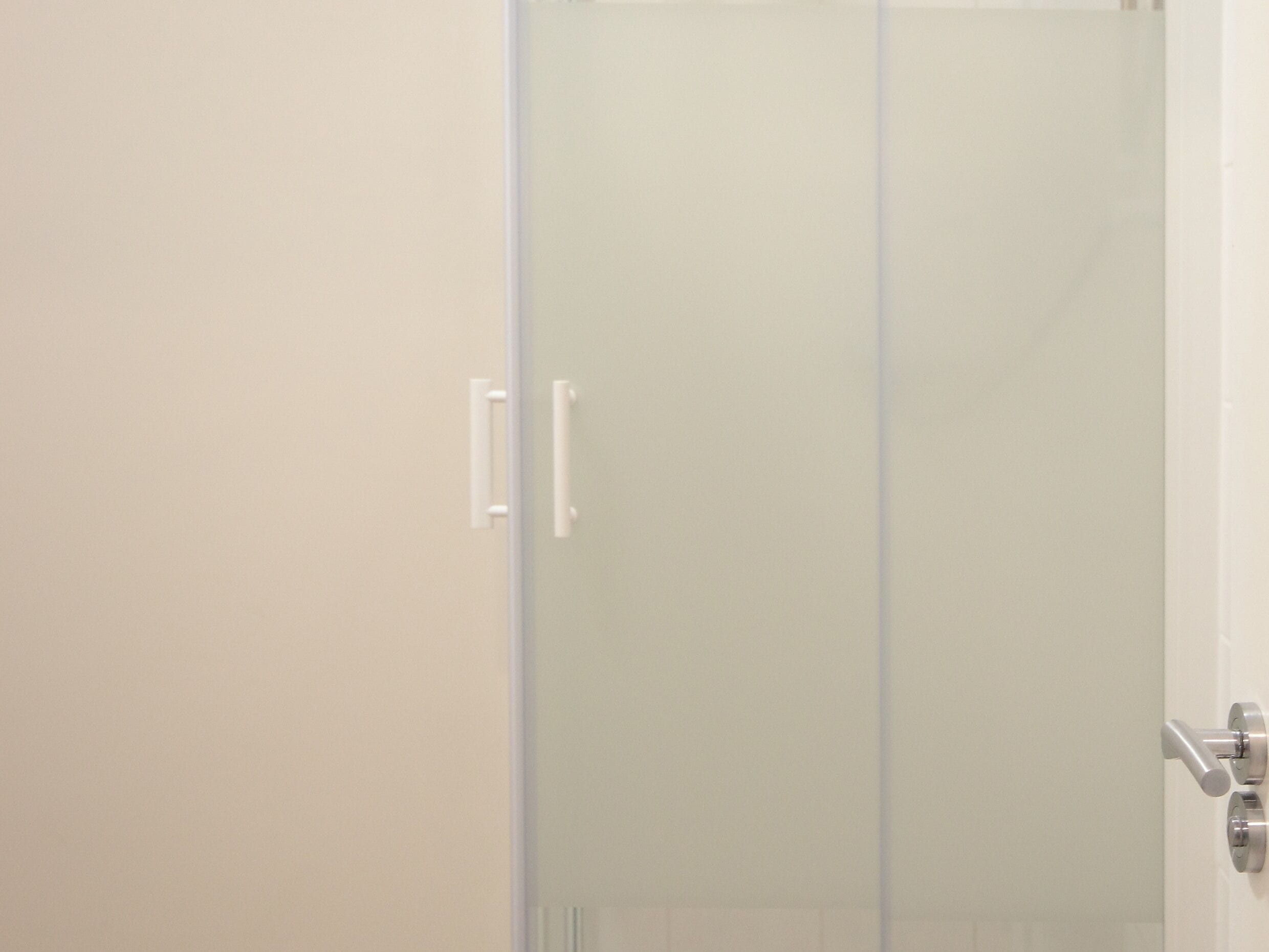 A bathroom with a glass shower door, a white sink, and a white toilet.