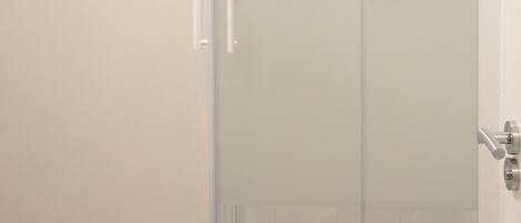 A bathroom with a glass shower door, a white sink, and a white toilet.
