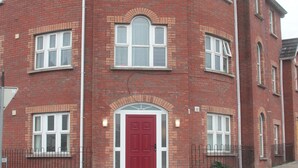 A red brick building with multiple windows and a central red door.