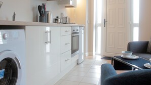 A modern kitchen with white cabinets, a built-in oven, and a washing machine.