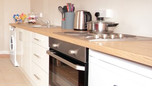 A modern kitchen with stainless steel appliances, a wooden countertop, and white cabinetry.