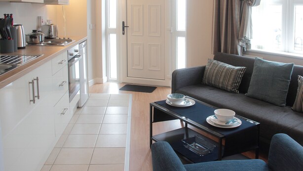 A modern kitchen with white cabinets and a dining area with a sofa and table.