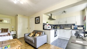 A compact living space with a sofa, a dining table, a kitchen area with appliances, and a bed. - Stunning Studio Apartment Castle View (Edinburgh)