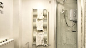 A bathroom with a glass shower enclosure, a towel rack with multiple towels, and a toilet. - Stunning Studio Apartment Castle View (Edinburgh)