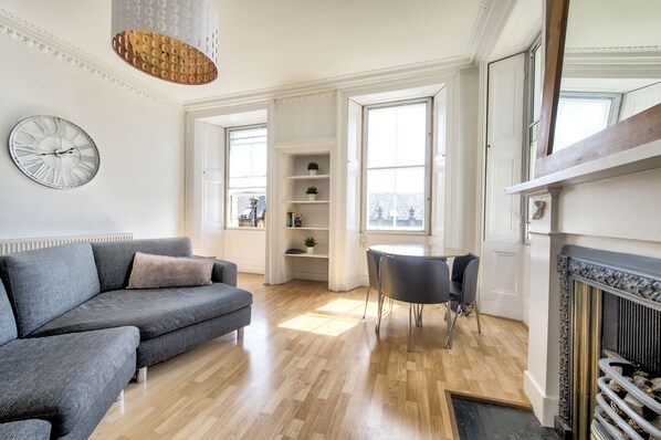 A modern living room with a grey sofa, a round table, and a fireplace. - Johnston Terrace Apartment (Edinburgh)
