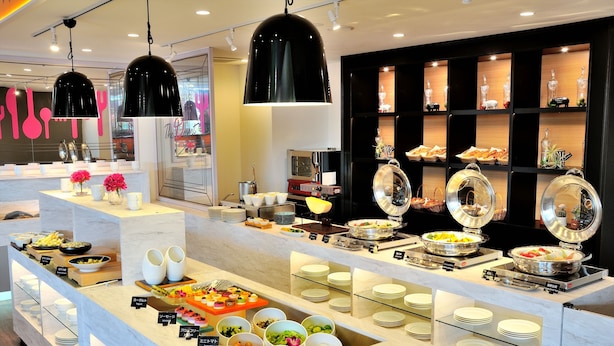 Un buffet proposant une variété de plats, avec différents postes de service et un décor intérieur moderne.