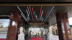L’entrée d’un hôtel, avec un tapis rouge, des portes en verre et un design moderne au plafond.
