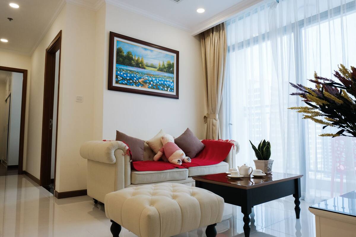 A living room with a sofa, ottoman, and a painting on the wall.