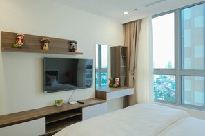 Ein modernes Hotelzimmer mit einem großen Bett, einem an einer Holzwand montierten Fernseher, einem Spiegel und Blick auf die Stadt durch große Fenster.