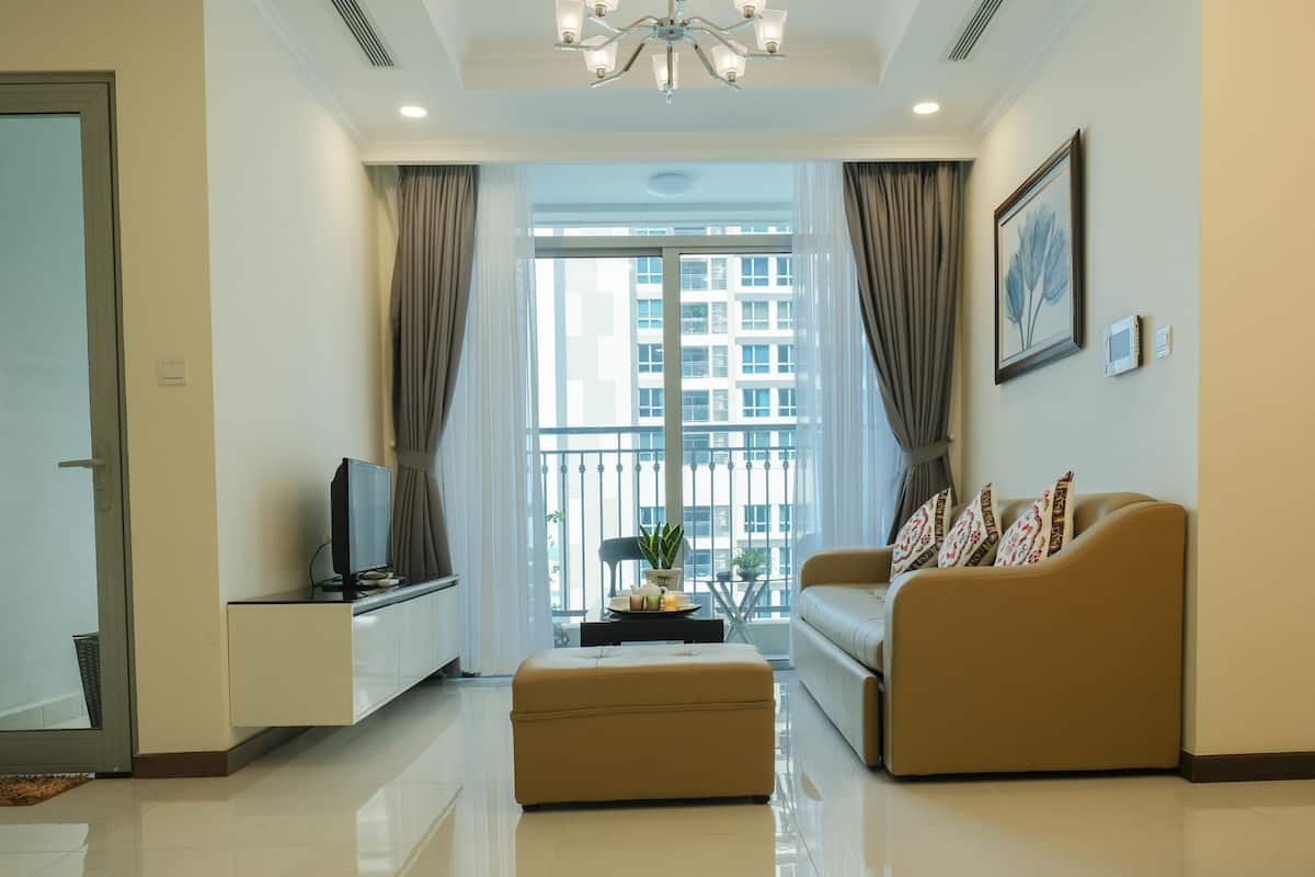 A modern living room with a sofa, ottoman, and a television on a stand.