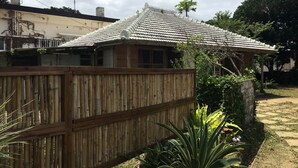 Ein traditionelles Haus mit Ziegeldach, Holzlattenzaun und Garten mit verschiedenen Pflanzen.