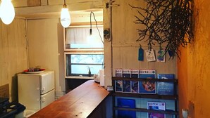 Eine kleine Küche mit Holzausstattung, einer langen Arbeitsplatte, hängenden Lampen und einem kleinen Kühlschrank.