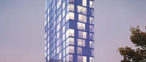 A modern high-rise building with a glass facade, multiple floors, and a prominent entrance at the base.