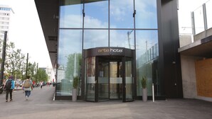 La entrada del Arte Hotel, con fachada de vidrio y puerta giratoria.