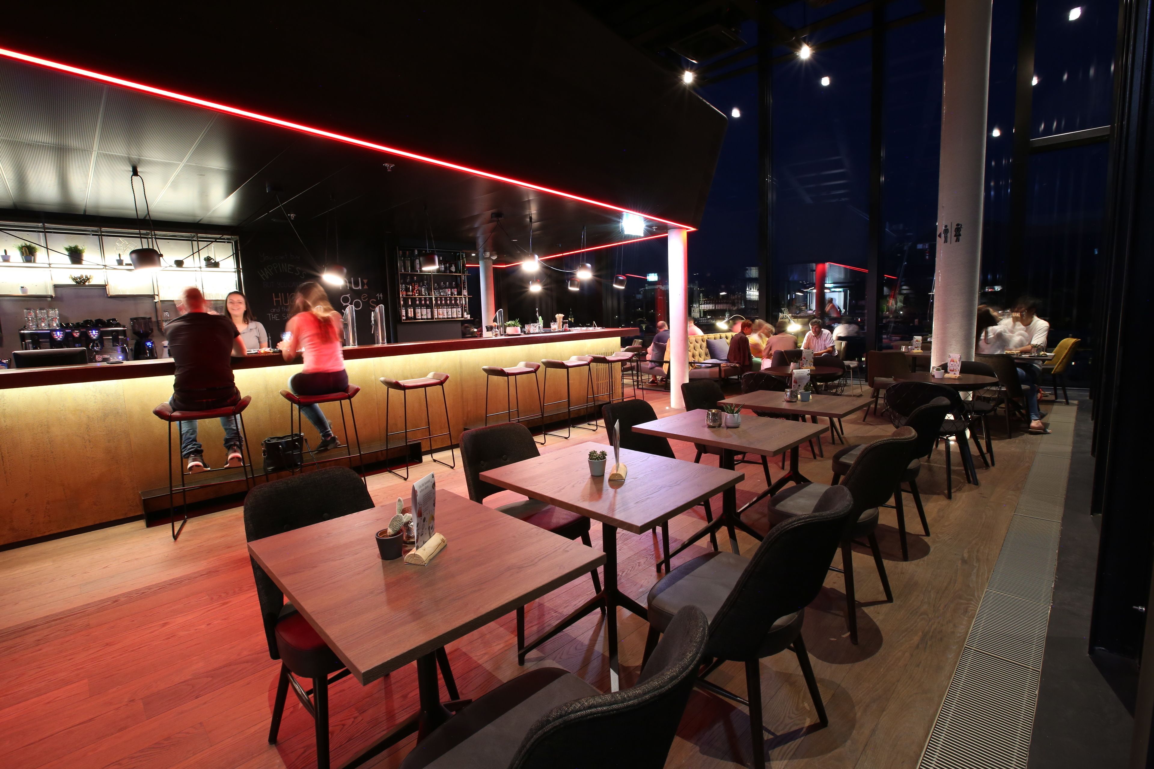 Ein modernes Restaurant mit Bar, Holztischen und -stühlen.