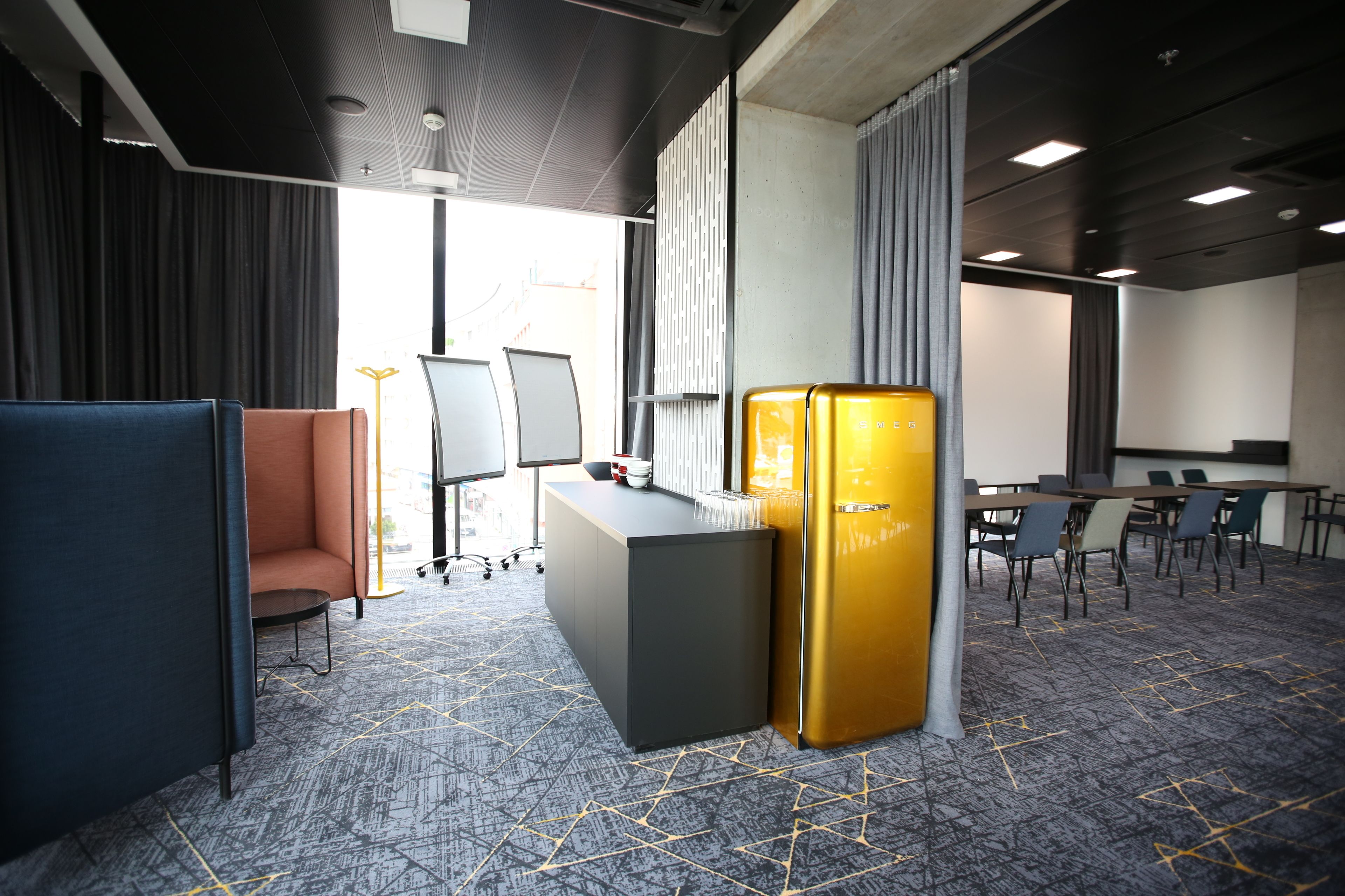 Une salle de conférence moderne équipée d’une grande table, de chaises, d’un pupitre et d’un réfrigérateur doré unique.