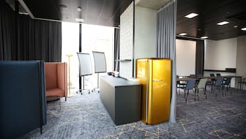 Une salle de conférence moderne équipée d’une grande table, de chaises, d’un pupitre et d’un réfrigérateur doré unique.