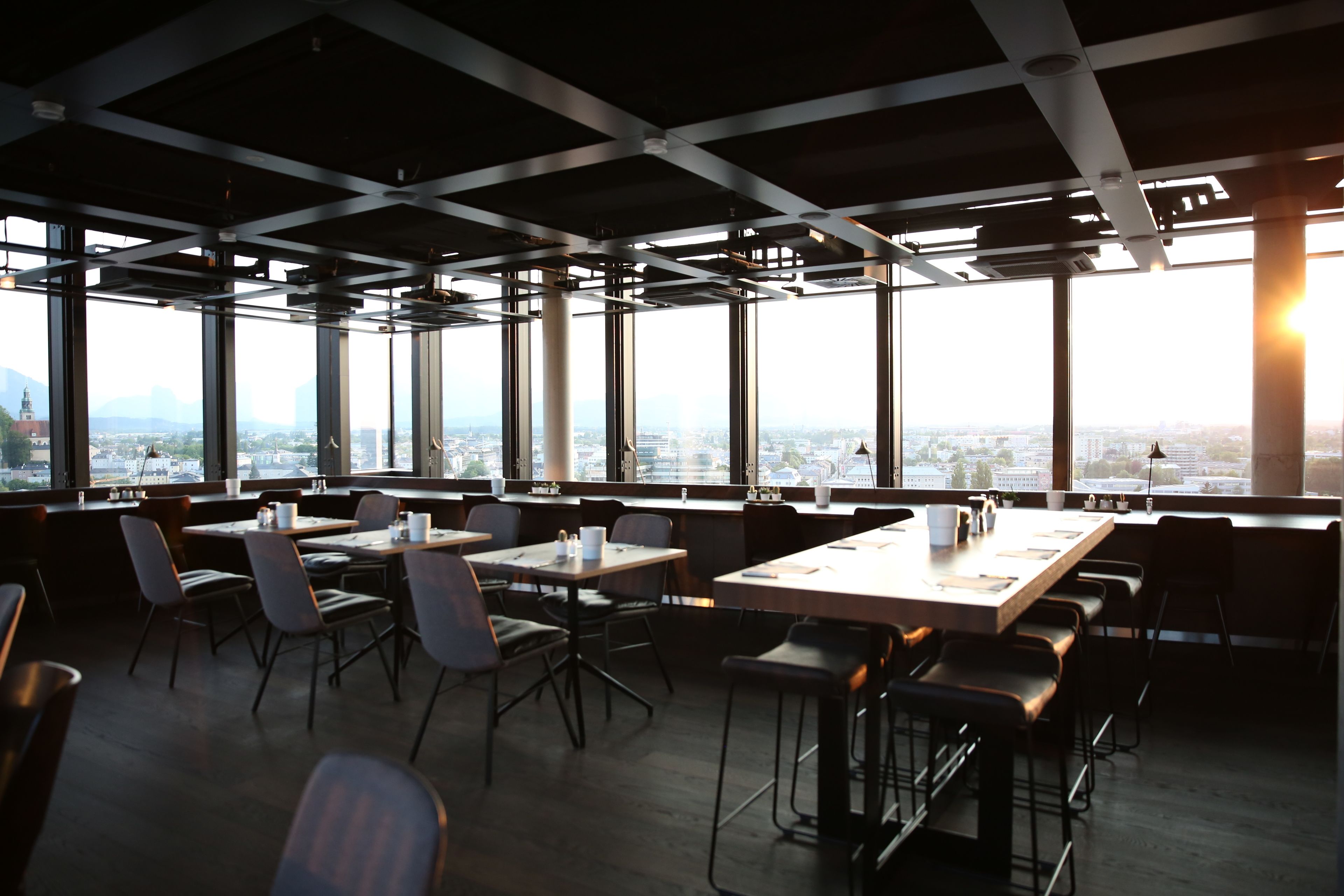 A modern conference room with large windows, high ceilings, and a city view.