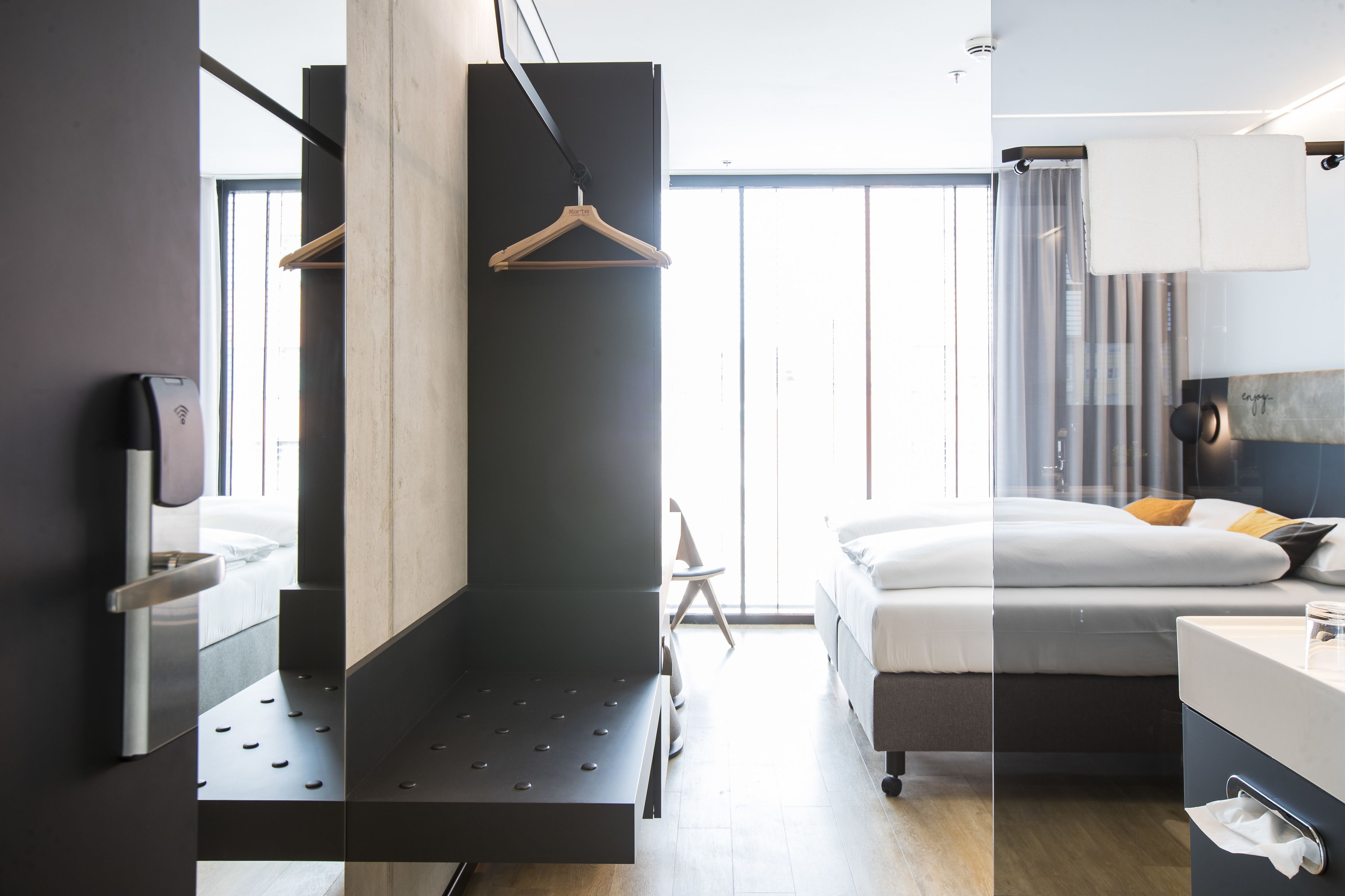 Una habitación de hotel moderna con cama, mesita de noche y lámpara colgante.