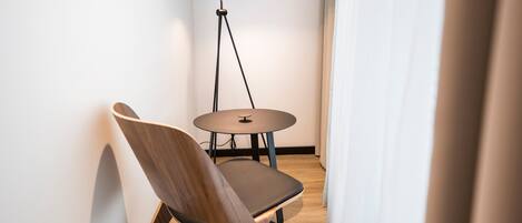A modern room with a wooden chair, a small round table, and a floor lamp.