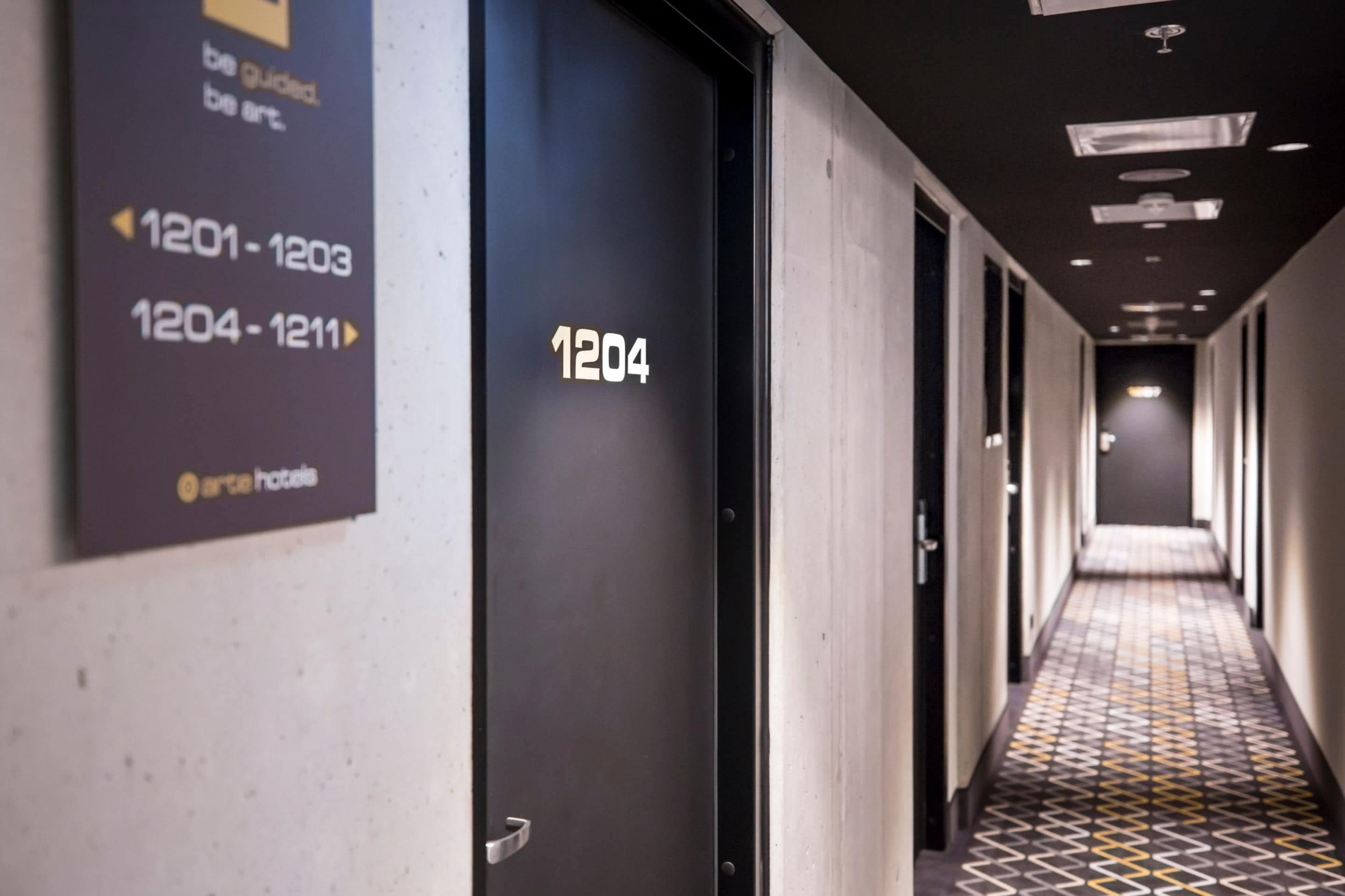 Pasillo de hotel con puertas numeradas del 1201 al 1203 y del 1204 al 1211.
