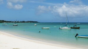 A beach with several boats anchored in calm waters, a sandy shore, and a clear sky. - O'Biches by Horizon Holidays (Trou aux Biches)