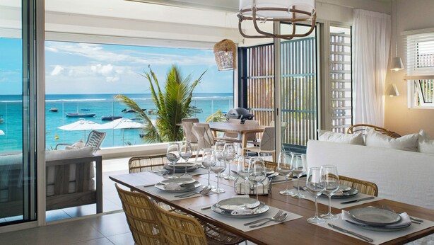 A dining area with a view of the ocean, a large window, and a balcony with outdoor furniture. - O'Biches by Horizon Holidays (Trou aux Biches)