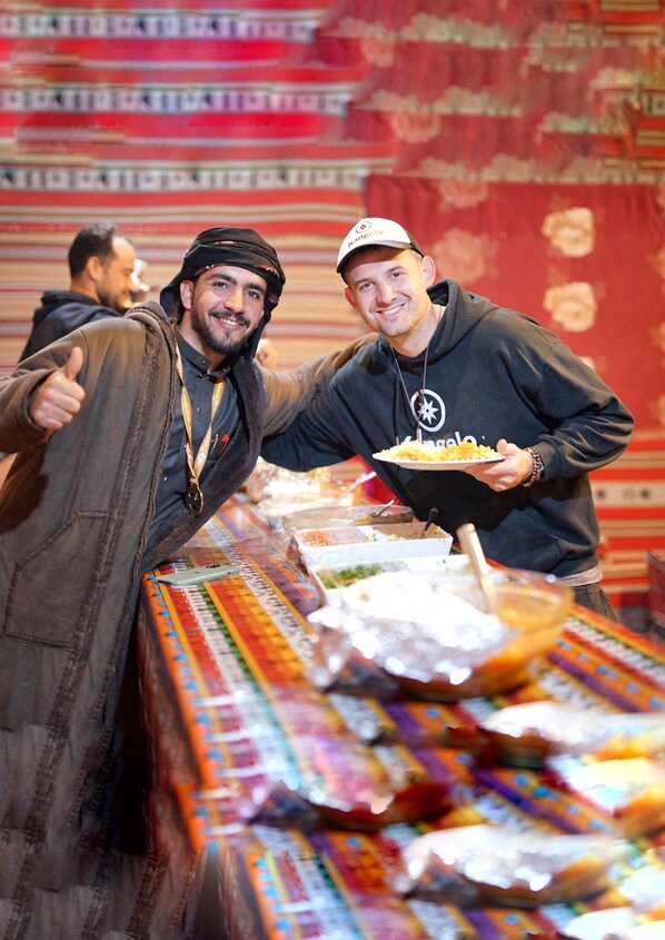 Two people at a buffet with a variety of food items on display.