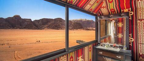 A room with a large window offering a view of a desert landscape.