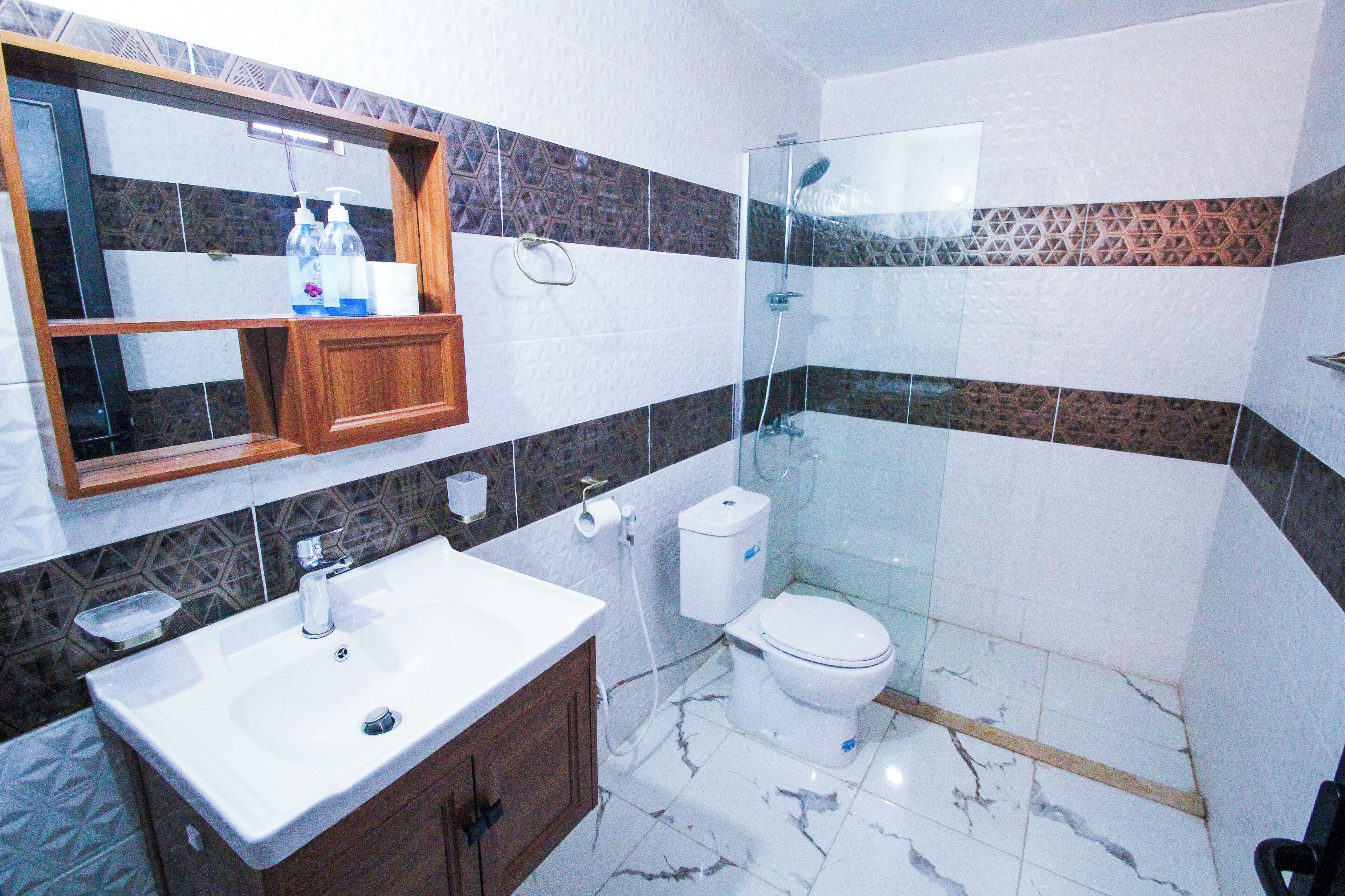 Ein Badezimmer mit Marmorwaschbecken, Toilette und einer Duschkabine aus Glas.