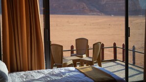 Una stanza con un letto, un tavolo e due sedie, con vista su un paesaggio desertico.