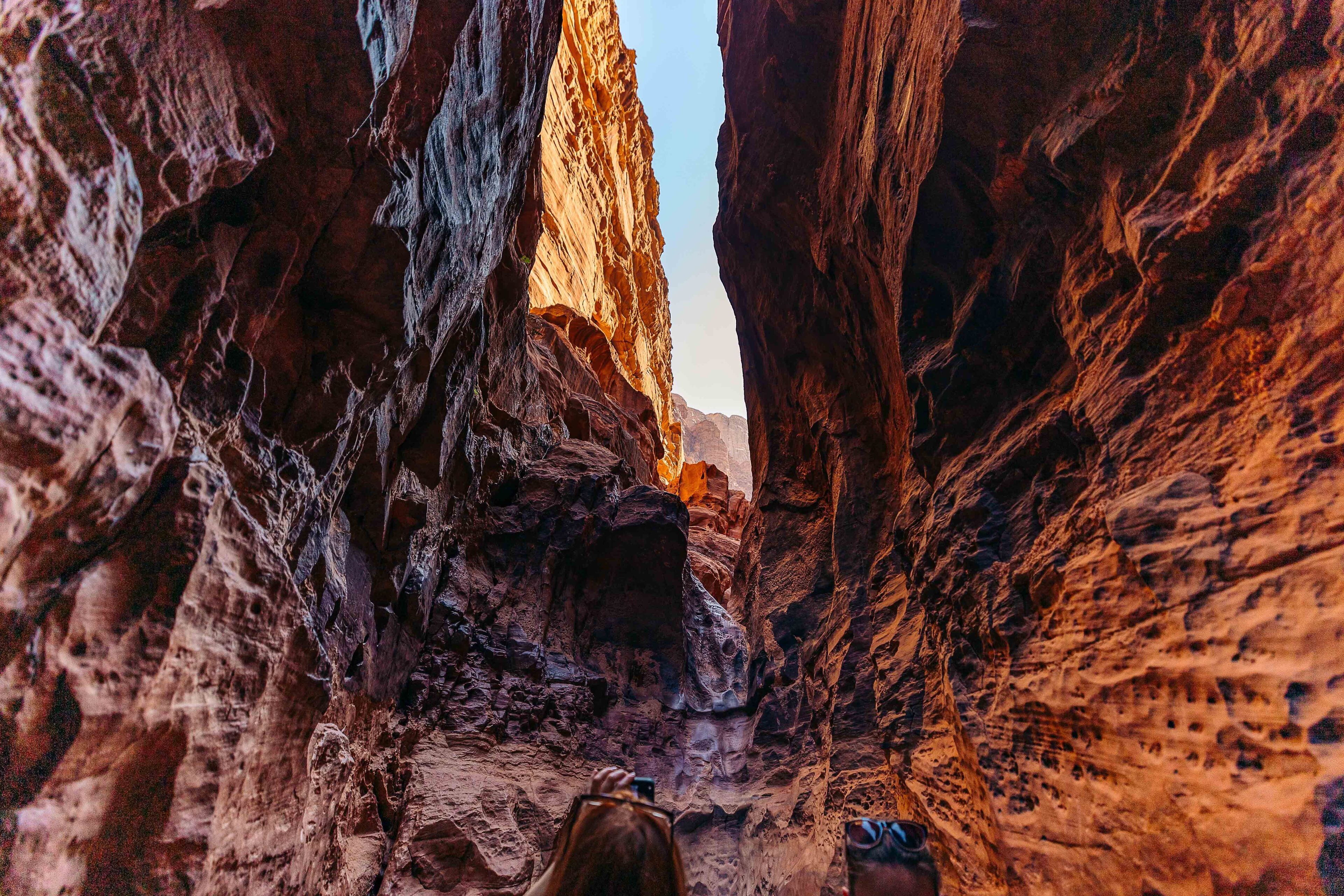 A narrow canyon with rugged rock walls and a clear sky.