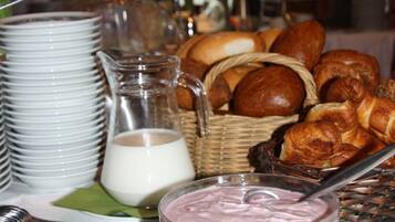 A breakfast buffet with various pastries, bowls of yogurt, and a pitcher of milk.