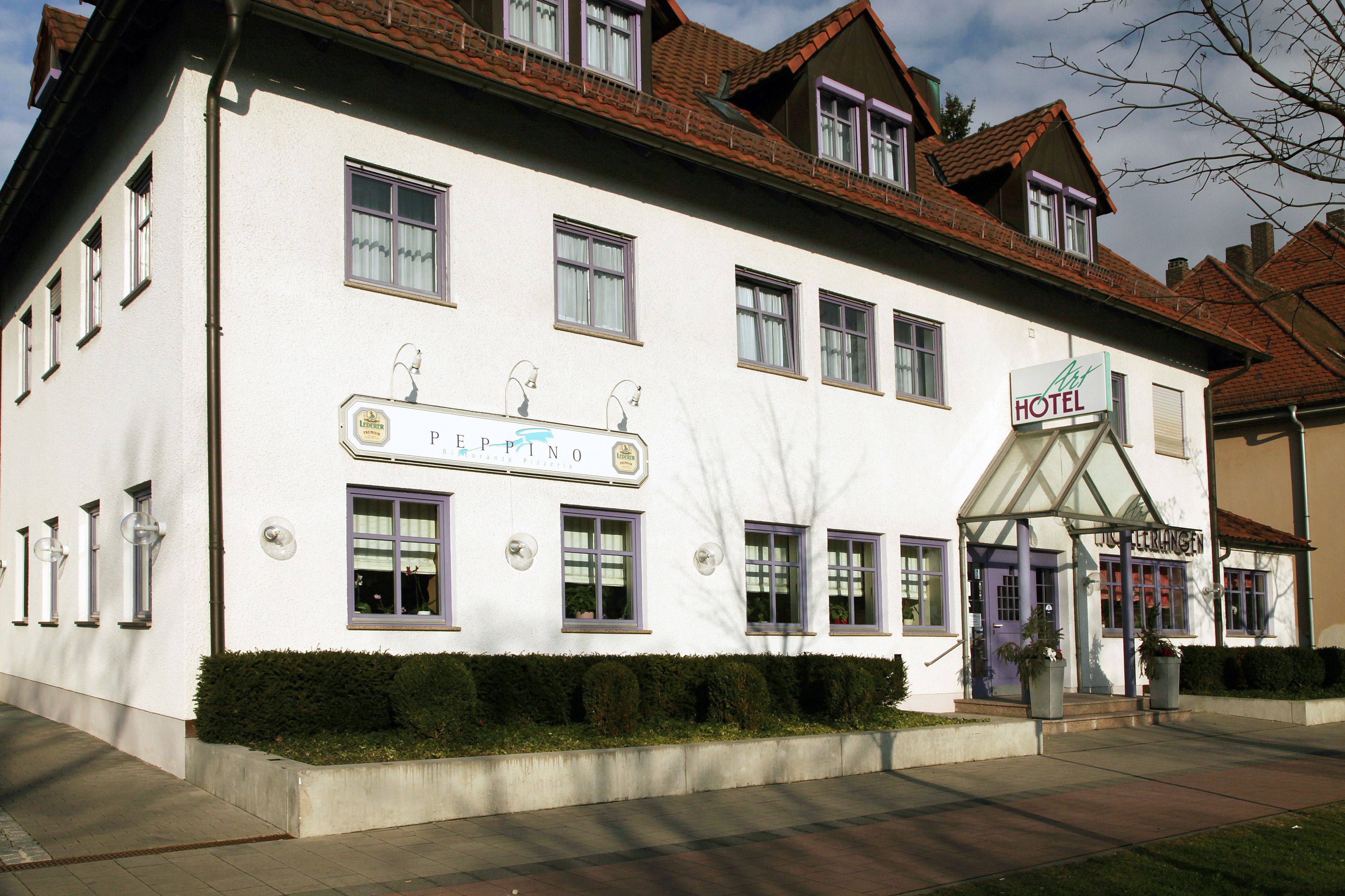 A hotel with a traditional European architectural style, featuring a prominent entrance with a glass canopy and a sign indicating it is a hotel.