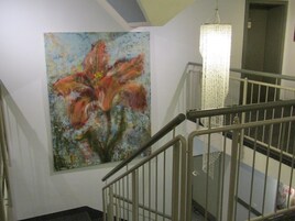 Una escalera con barandilla de metal y un cuadro de una flor en la pared.