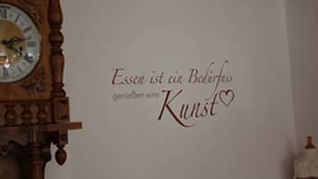 A wall with a clock and a decorative phrase in German.