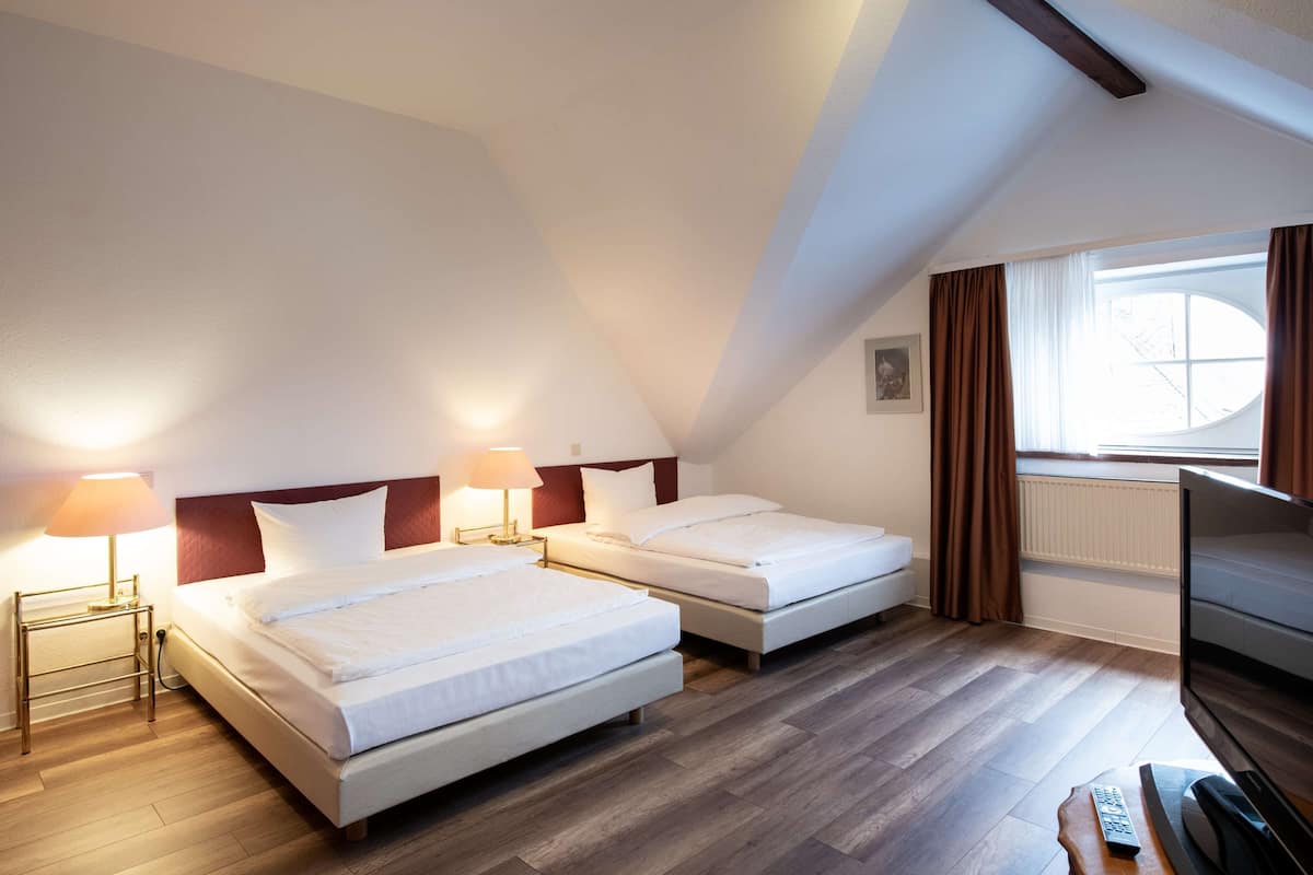 A hotel room with two beds, a TV, and a window with curtains.
