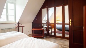 Una camera da letto con soffitto spiovente, un armadio in legno e un letto.