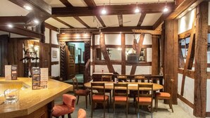 Un'osteria tradizionale con travi a vista in legno, un'area bar in legno e un tavolo centrale con sedie.