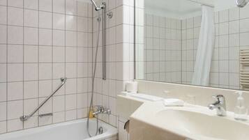 A bathroom with a bathtub, a shower, a sink, and a mirror.