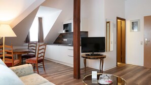 Un soggiorno moderno con un divano, un tavolo da pranzo con sedie, una televisione e un angolo cottura sullo sfondo.