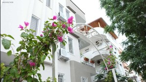 Un immeuble à plusieurs étages doté de balcons, de climatiseurs et d’une façade blanche.