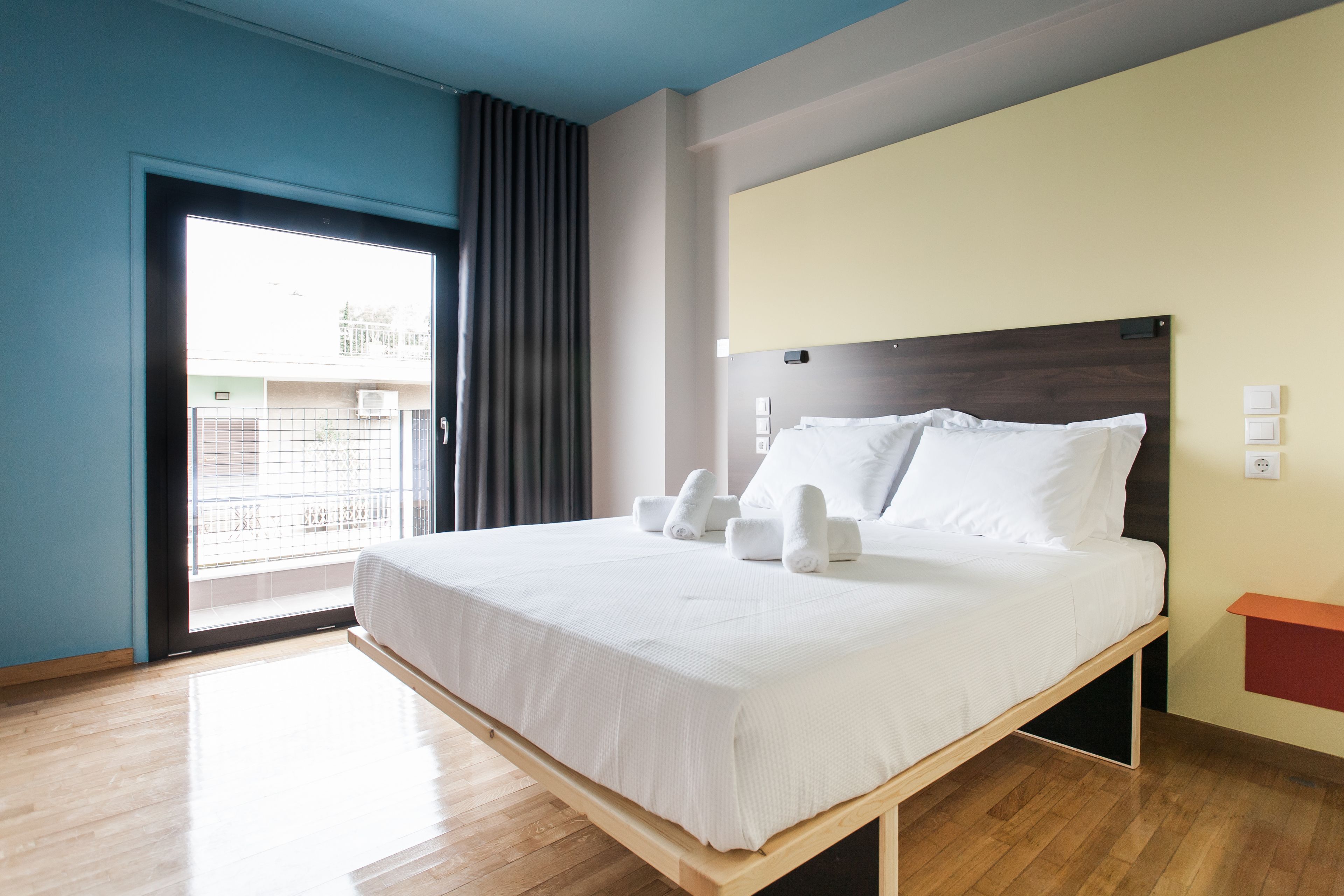 A modern hotel room with a large bed, a window with curtains, and a view of the outside.