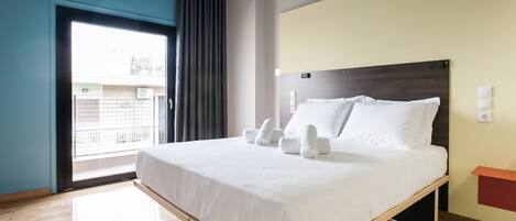 A modern hotel room with a large bed, a window with curtains, and a view of the outside.